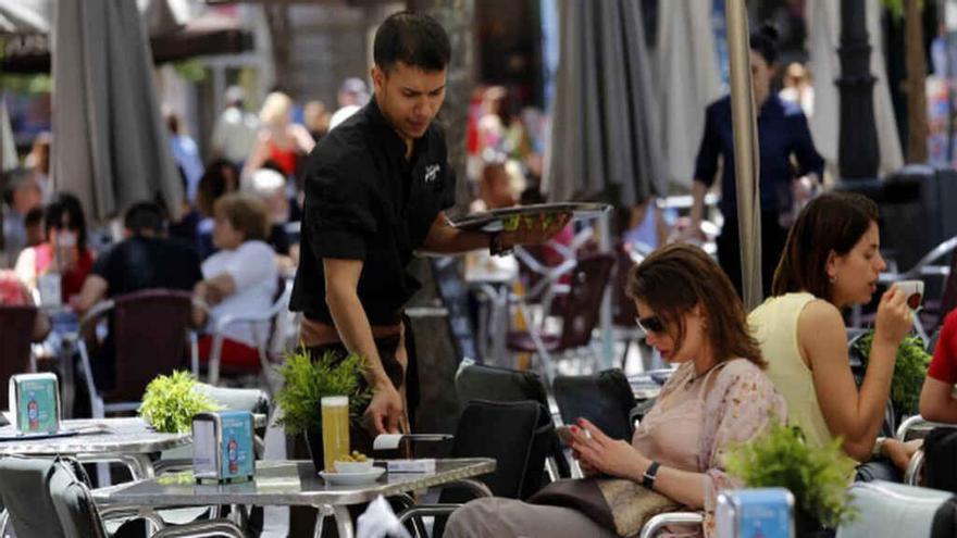 Un &#039;barman&#039; atiende a una clienta en una mesa de un velador.