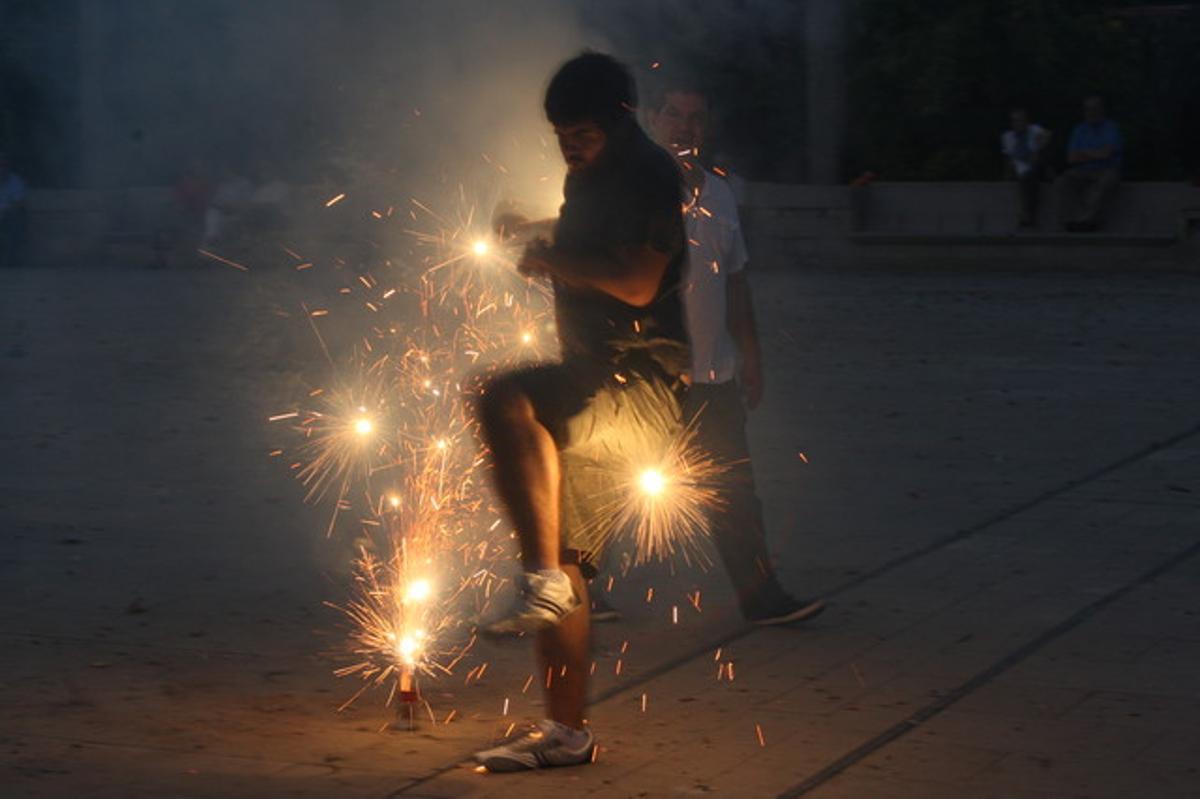 Un jove celebra amb petards la revetlla de Sant Joan a Barcelona.