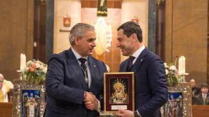 El Hermano Mayor de la Hermandad de Montserrat de Sevilla, Juan Coto, entrega un recuerdo al presidente de la Junta de Andalucía, Juan Manuel Moreno Bonilla