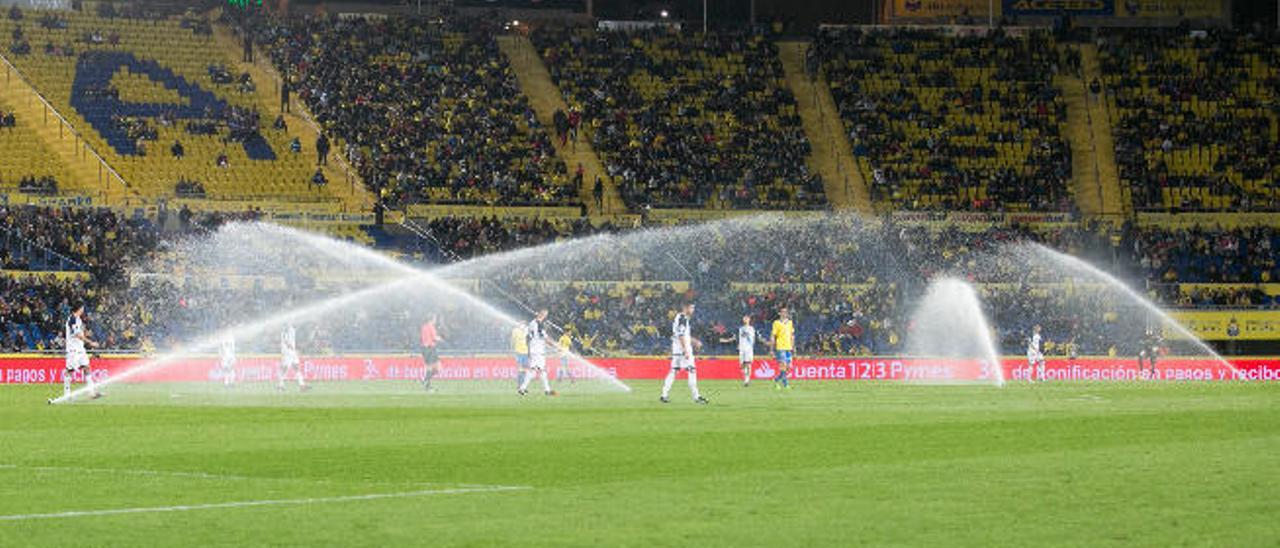 En la primera imagen, los aspersores del Estadio de Gran Canaria, que saltaron en medio de la segunda mitad. En el centro de esta serie, uno de los palcos donde ven los partidos los futbolistas con Jonathan Viera y Javi Castellano entre ellos. Debajo, Juan Carlos Valerón entrega a Vicente Gómez una camiseta en homenaje por sus 200 partidos con la UD Las Palmas.