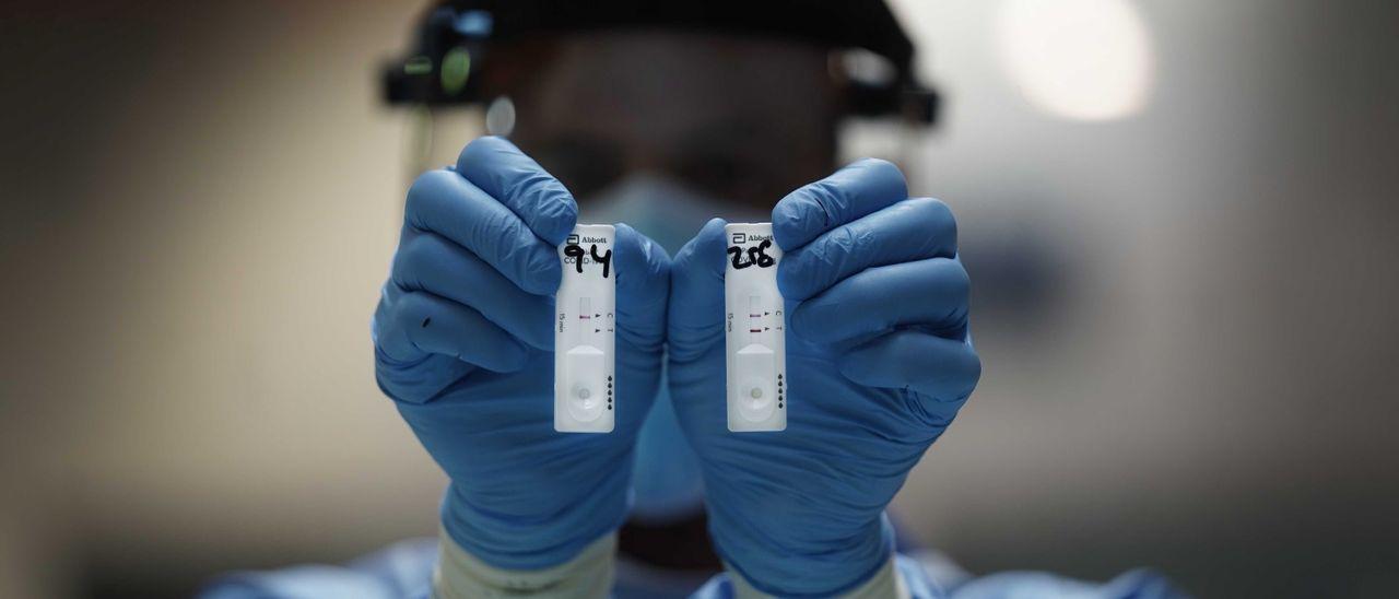 Una sanitaria sostiene dos pruebas de antígenos en una imagen de archivo