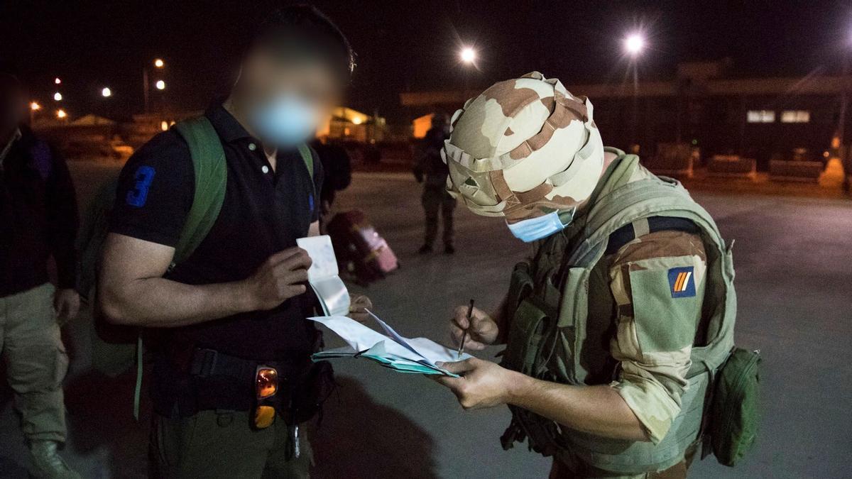 Fotografía facilitada por el Ministerio de Defensa francés muestra a un soldado francés comprobando la identificación de un hombre en su lista de pasajeros antes de abordar el avión militar francés A400M en la sección militar del aeropuerto de Kabul.