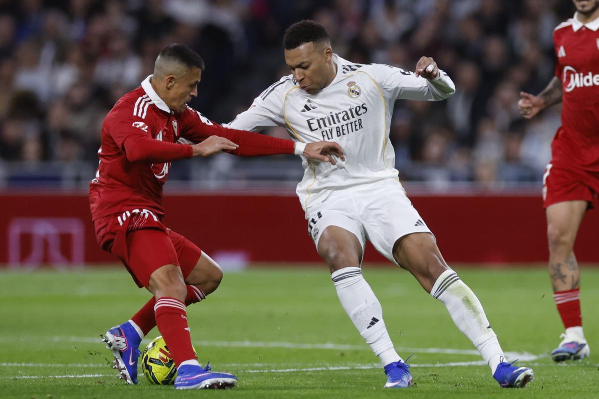 El delantero del Real Madrid Kylian Mbappé (d) disputa un balón con el delantero del Sevilla Alexis Sánchez (i) durante el encuentro de la jornada 17 de LaLiga entre Real Madrid y Sevilla FC celebrado este sábado en el estadio Santiago Bernabéu, en Madrid.