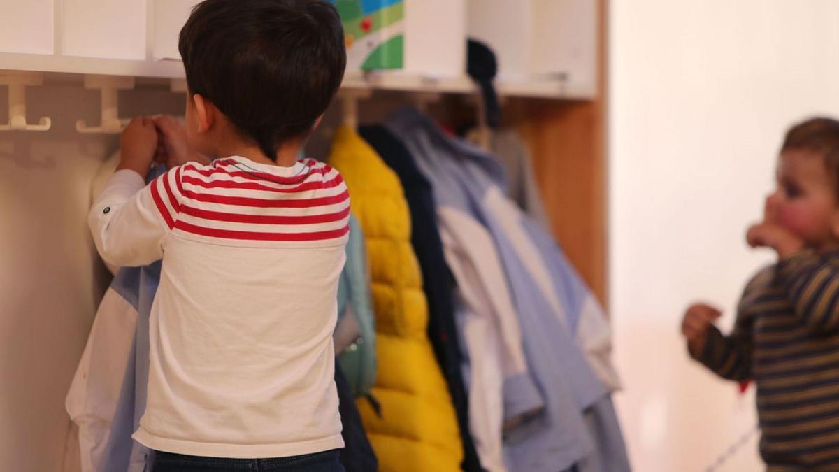 Un niño del aula de Infantil coloca su abrigo en el perchero antes de entrar en clase.