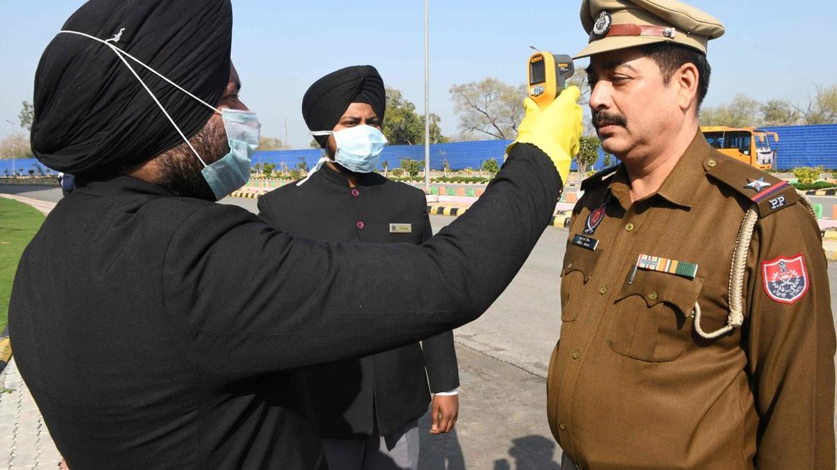 Miembros del personal de un hotel de Amritsar (India) toman la temperatura de un personal de la policía en la entrada del establecimiento, este domingo, para detectar si tiene coronavirus