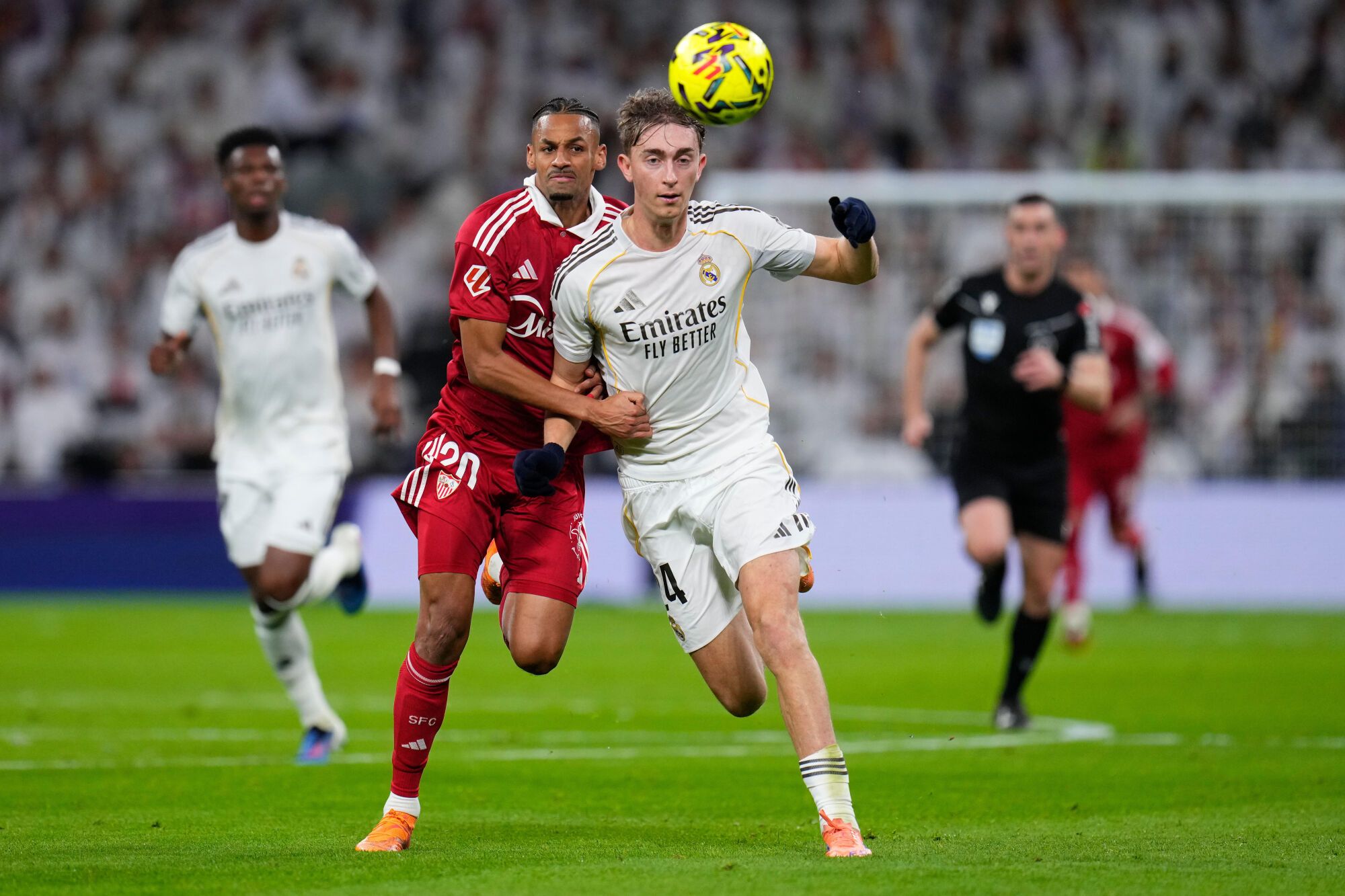 Real Madrid's Dean Huijsen, right holds of the challenge of Sevilla's Djibril Sow during the Spanish La Liga soccer match between Real Madrid and Sevilla in Madrid, Spain, Saturday, Dec. 20, 2025. (AP Photo/Manu Fernandez). EDITORIAL USE ONLY/ONLY ITALY AND SPAIN