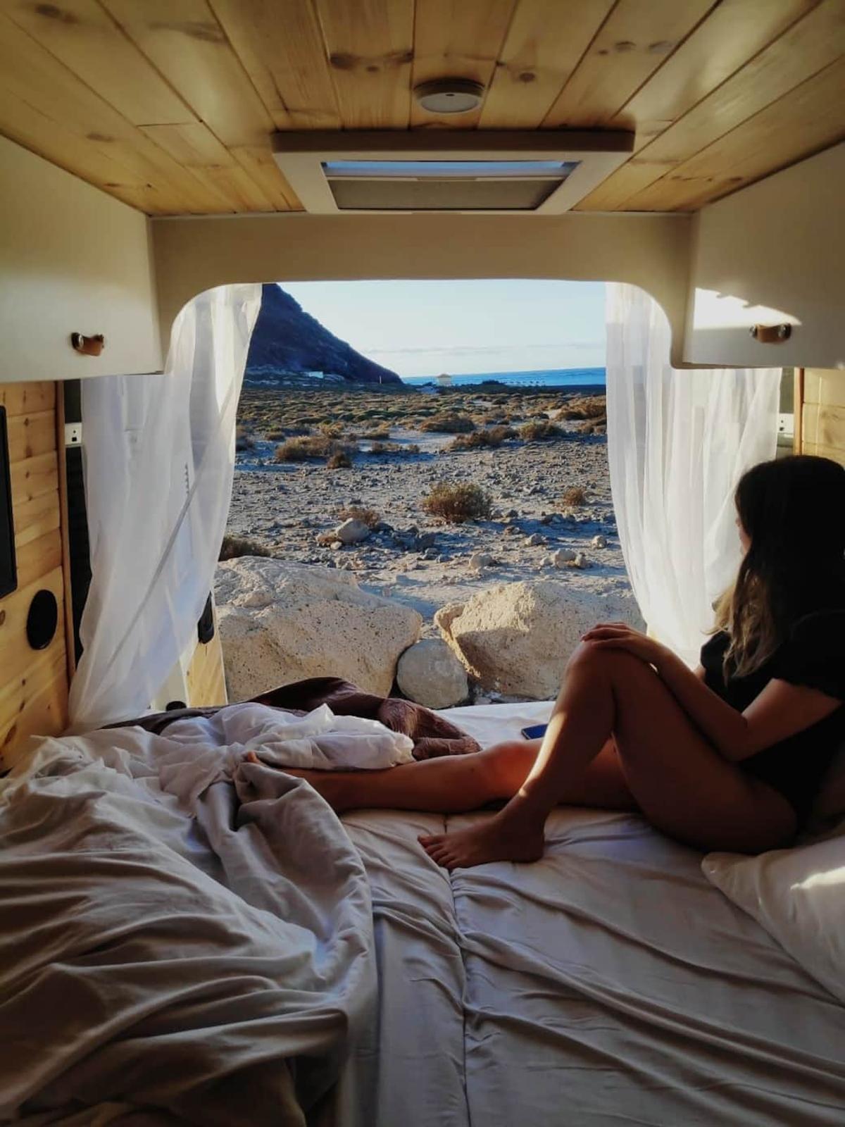Una joven disfruta de las vistas de una playa desde una caravana.