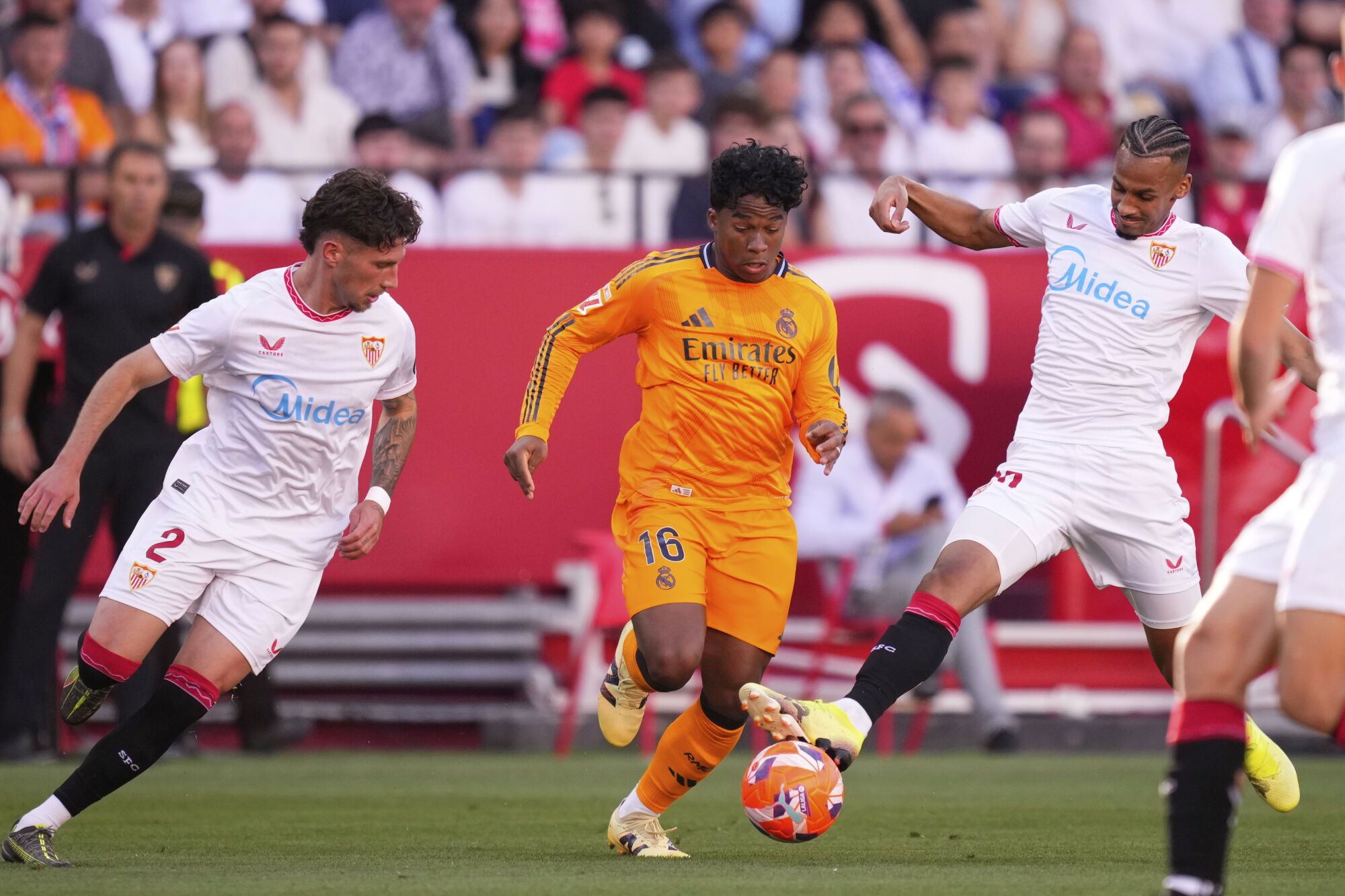 Real Madrid's Endrick, centre, challenges for the ball with Sevilla's Jose Angel Carmona, left, and Sevilla's Djibril Sow during the Spanish La Liga soccer match between Sevilla and Real Madrid at the Ramon Sanchez Pizjuan stadium in Seville, Spain, Sunday, May 18, 2025. (AP Photo/Jose Breton)