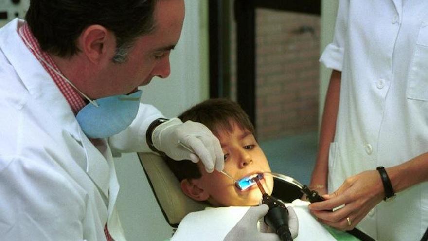 Un dentista revisa la boca a un niño en la consulta.