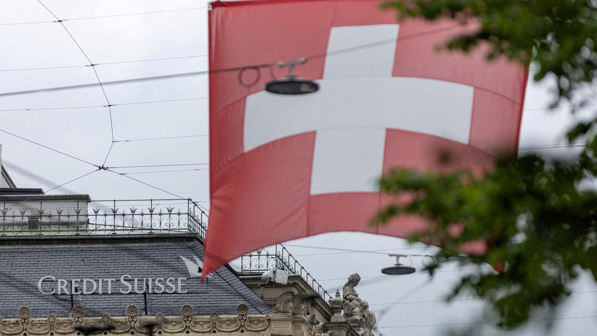 FILE PHOTO: A Swiss flag is seen in front of a logo of Swiss bank Credit Suisse in Zurich