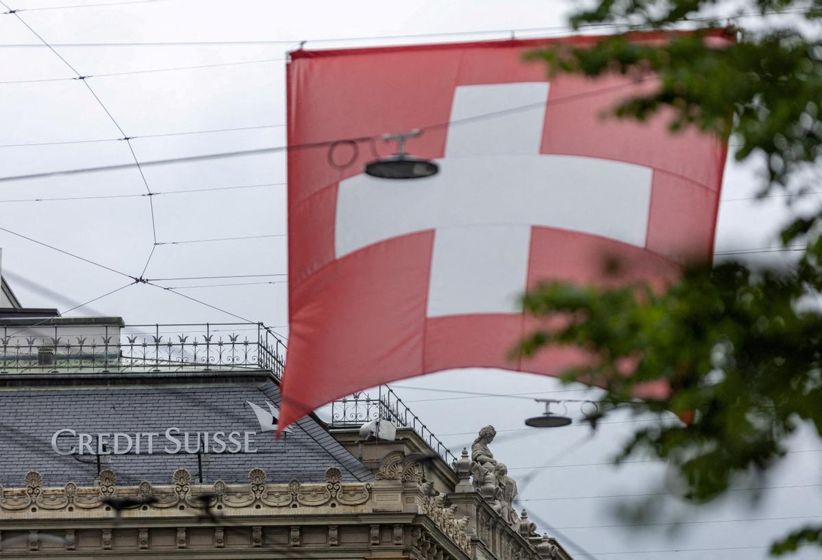 FILE PHOTO: A Swiss flag is seen in front of a logo of Swiss bank Credit Suisse in Zurich