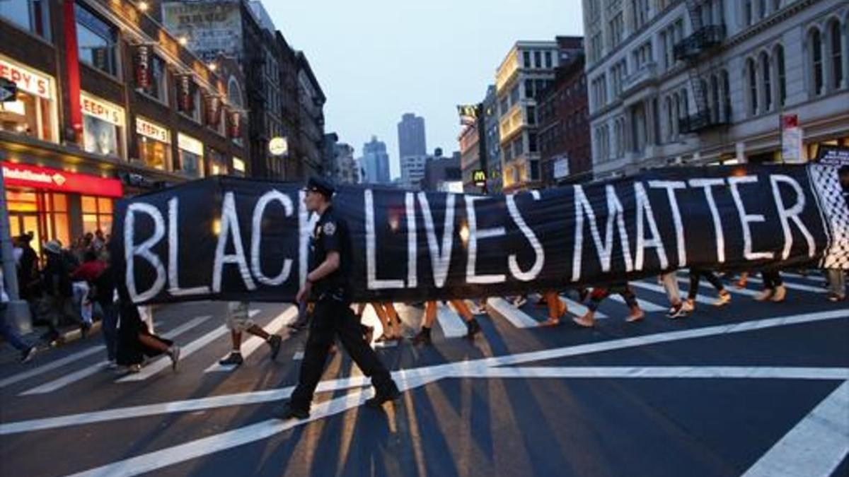 Un policía acompaña la manifestación por la calles de Nueva York del movimiento civil Black Lives Matter (la vida de los negros importa), ayer domingo.