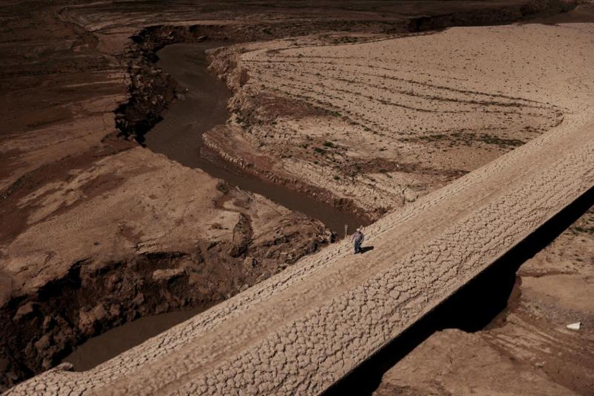 Un hombre camina sobre el suelo agrietado del embalse de Baells mientras el suministro de agua potable ha caído a su nivel más bajo desde 1990 debido a la sequía extrema en Cataluña, en el pueblo de Cersc, en la región de Bergueda, España, 14 de marzo de 2023.