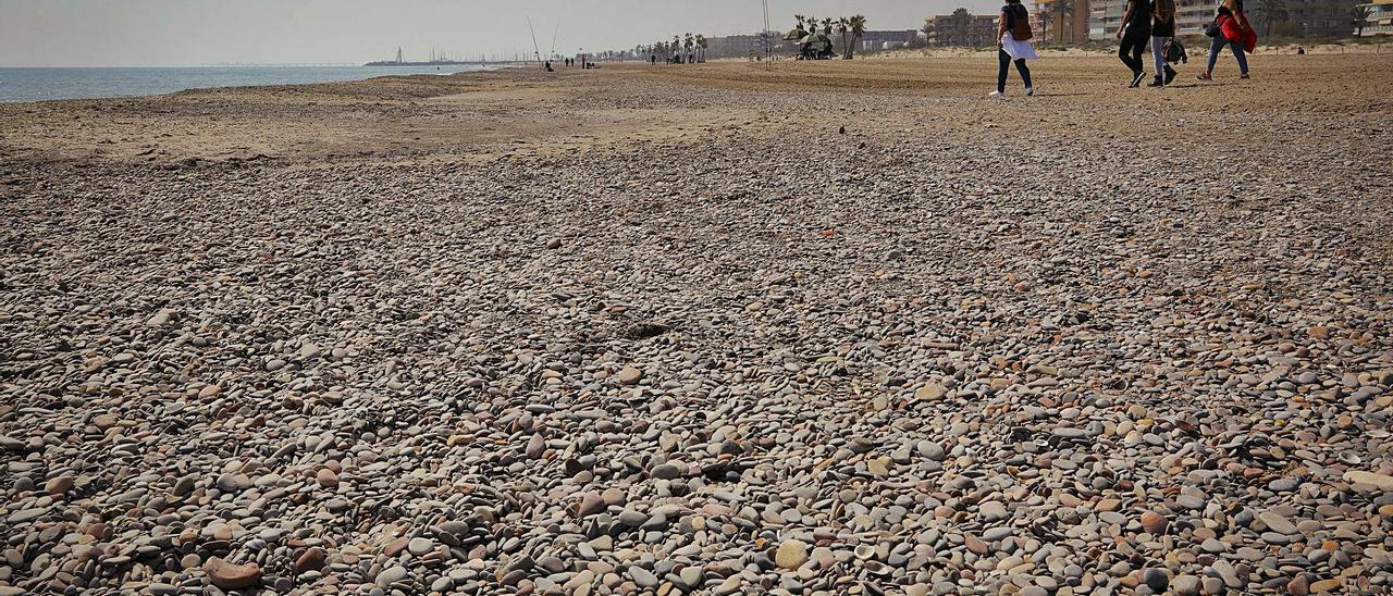 Varias personas paseando por el tramo  norte de Canet donde se ven más piedras.  |  TORTAJADA