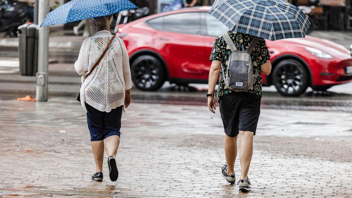 Dos personas caminan bajo la lluvia en Madrid.