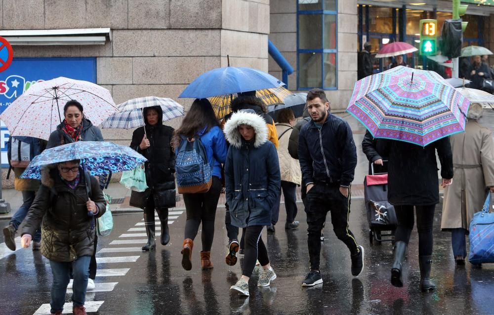 Viandantes tratan de protegerse de la lluvia, en el centro de Vigo