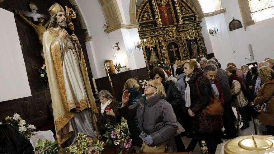 Asistentes a la celebración, ayer, en el interior de la iglesia parroquial de Santa Cruz de Jove, besan la reliquia de San Blas.