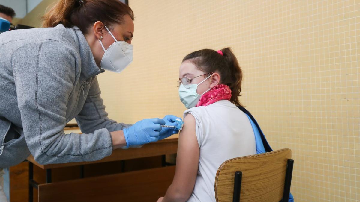 Una niña recibe la vacuna covid en un centro escolar de València