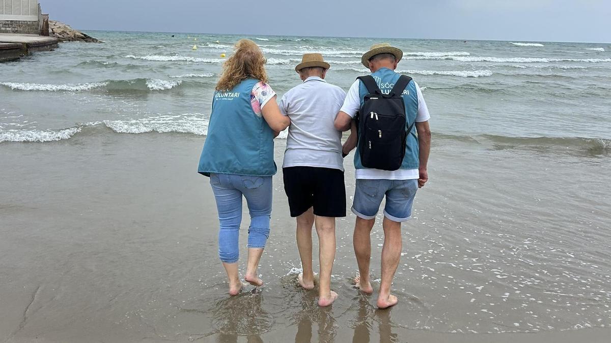 Dos voluntaris acosten al mar una persona participant en la sortida