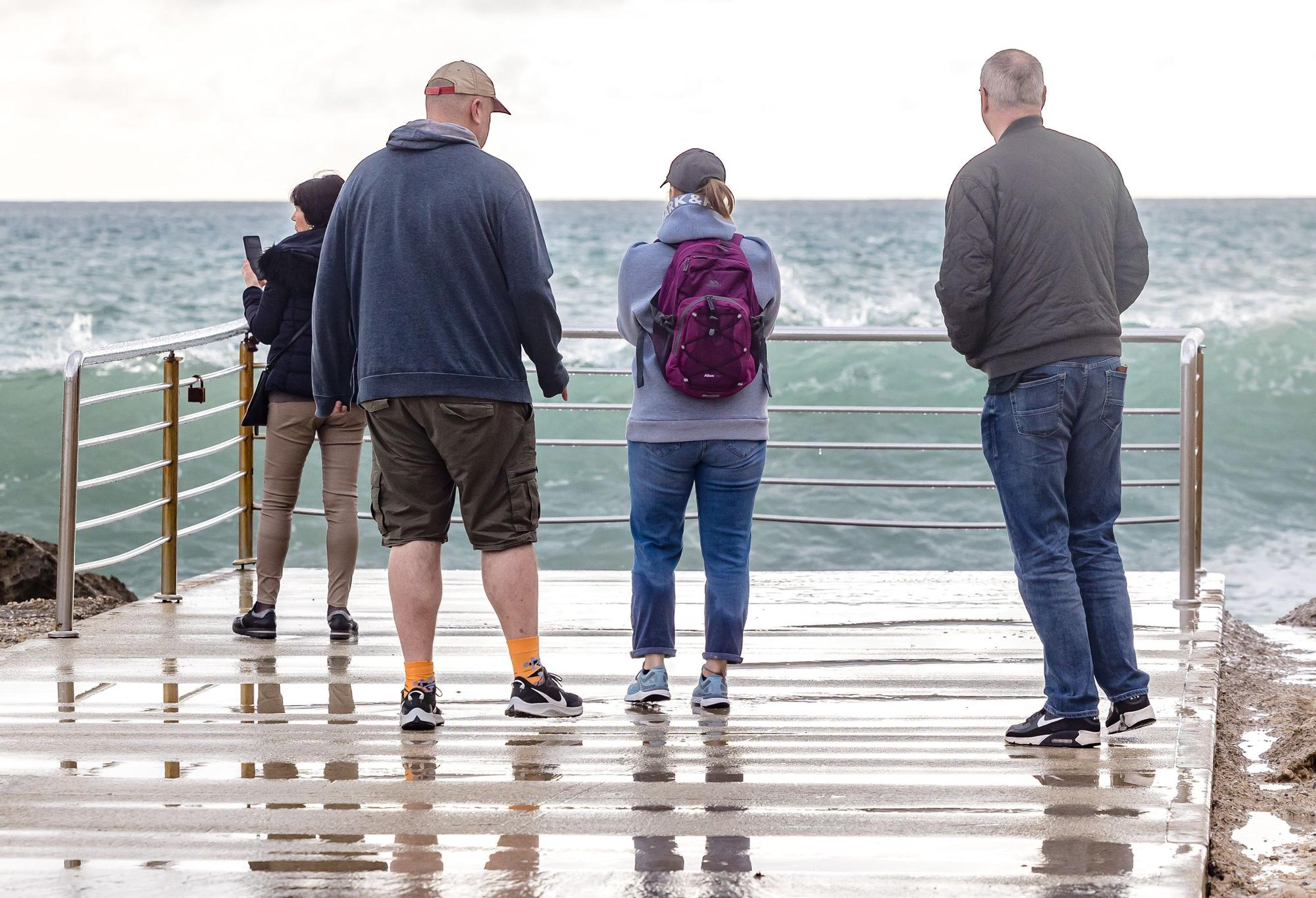 Turistas y paseantes observan el temporal de mar en la Cala de Finestrat