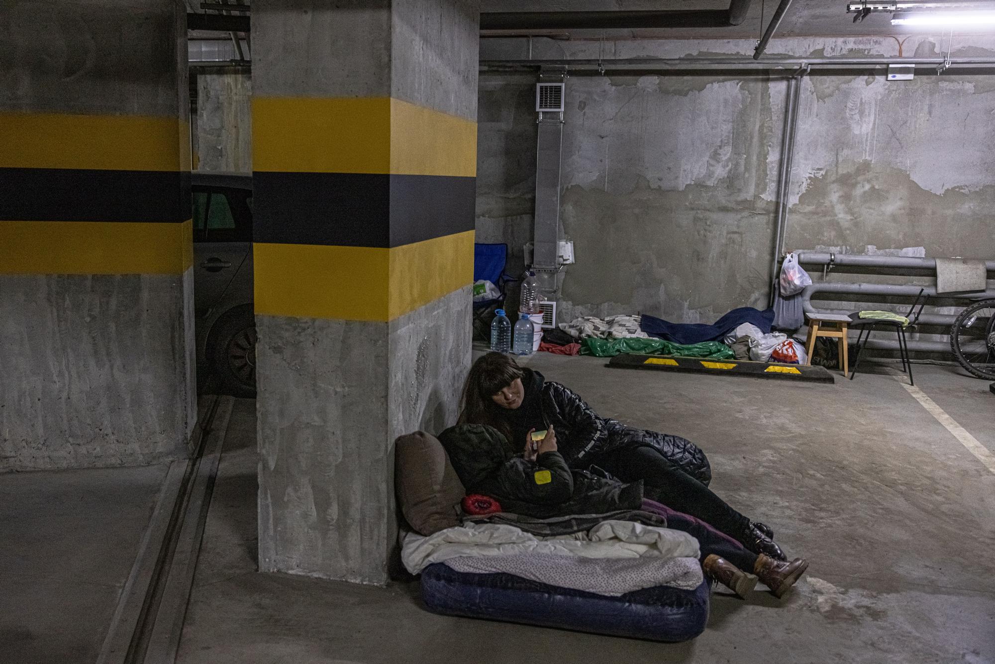 Gente descansando en un parking, utilizado como refugio antibombas, en Ucrania.