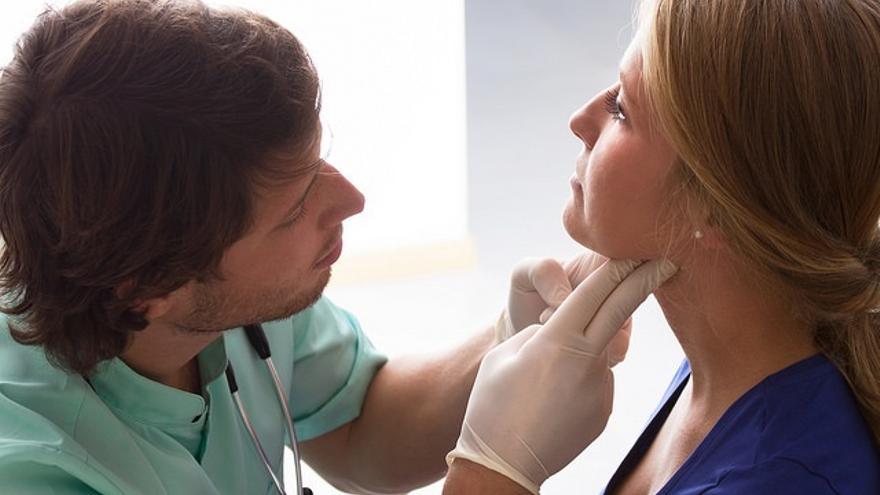 Un médico examina la garganta de una paciente.