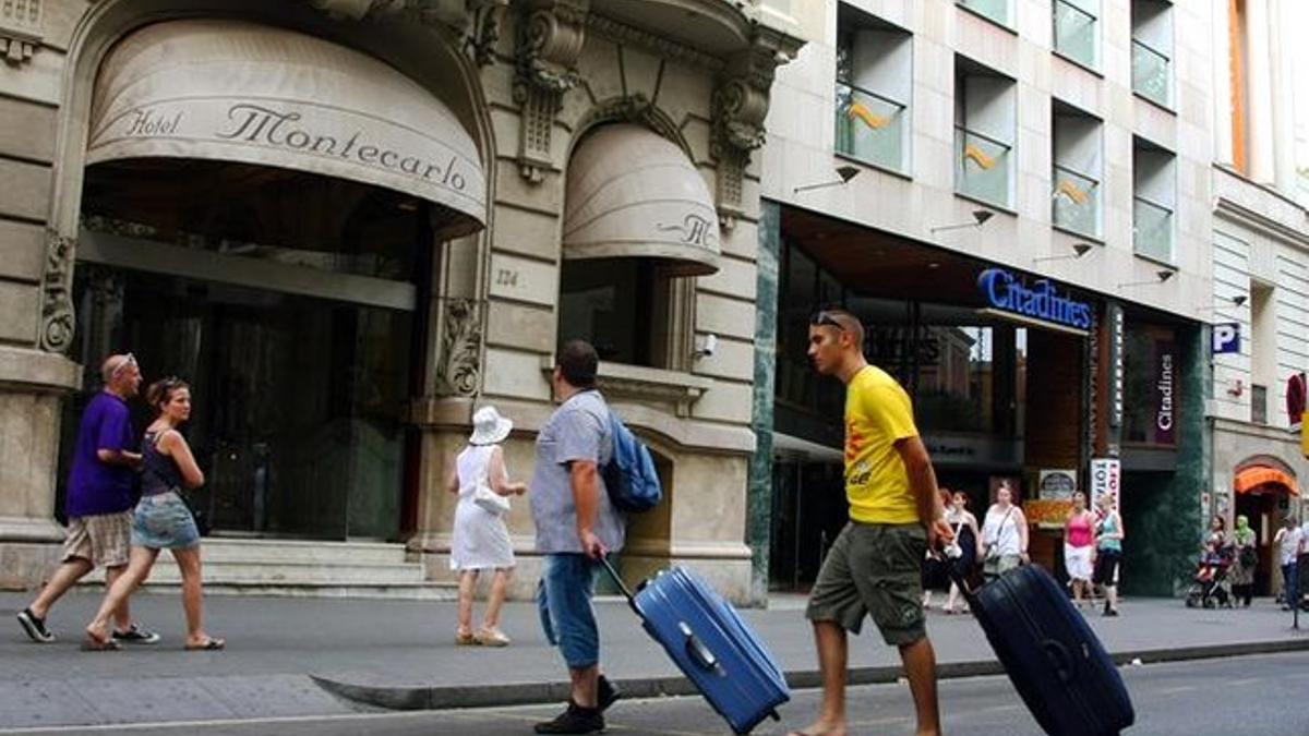 Dos turistas cruzan la Rambla cargados con maletas camino de su hotel.