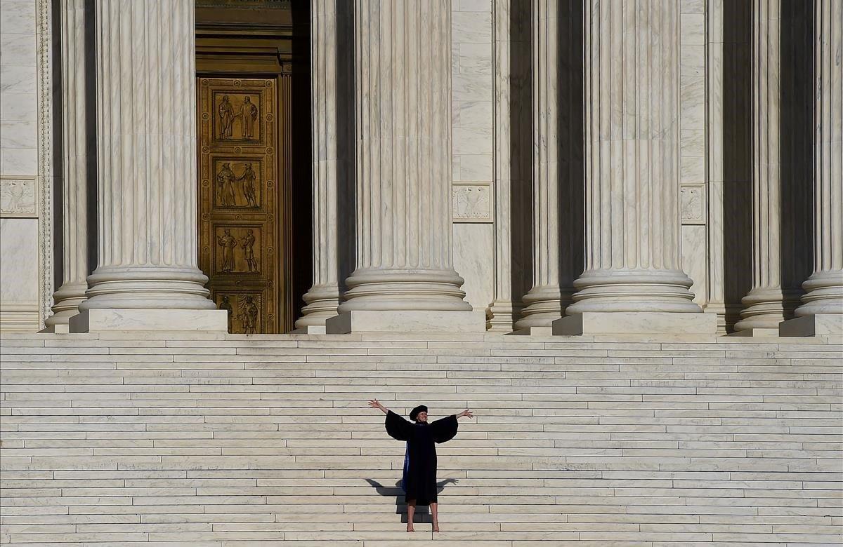 Un graduado posa en los escalones de la Corte Suprema cuando las ceremonias de graduación en todo el país se cancelan debido a la pandemia de coronavirus.