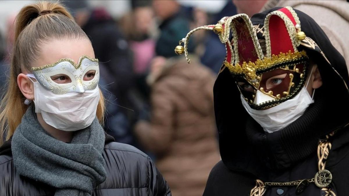 Asistentes con mascarillas protectoras en el carnaval de Venecia, que ha quedado suspendido.