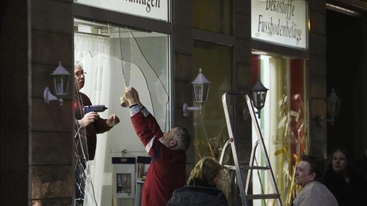 Unos hombres reparan los escaparates de una tienda rotos por los manifestantes ultraderechistas en Leipzig.