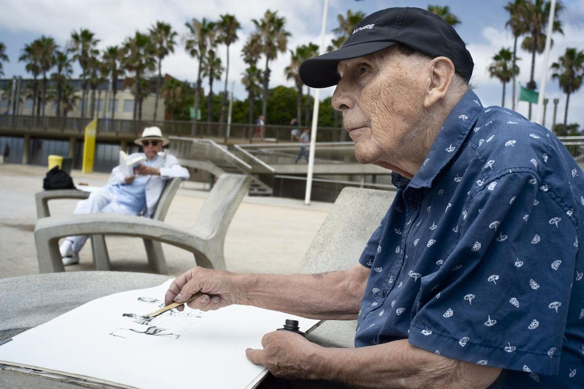 Joan Bueno, en plena tarea, en la Barceloneta y bajo atentan mirada de un elegante lector.