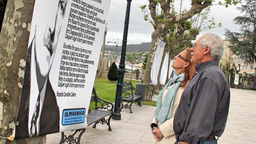 Dous veciños observan un dos paneis pendurados das árbores da Alameda de Marín. // Santos Álvarez