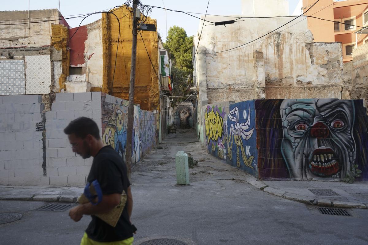 Un hombre pasa junto a varios grafitis en el barrio malagueño de Lagunillas, conocido por su arte urbano y su carácter obrero, pero teme desaparecer por la turistificación y el éxodo forzado de sus vecinos, quienes con esfuerzo luchan para mantener sus viviendas y la esencia del vecindario.