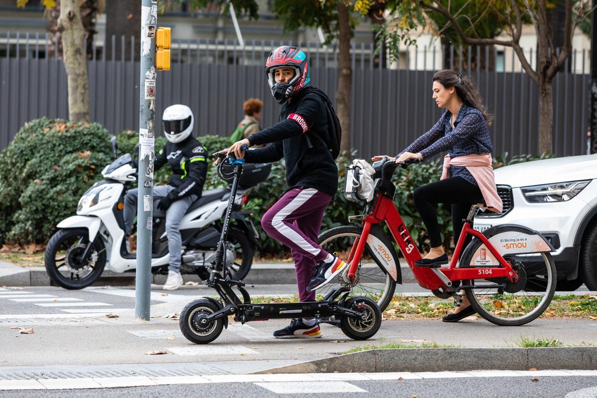 Usuario de patinete eléctrico con casco integral por las calles de Barcelona