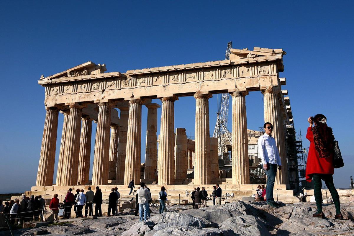 Varios turistas toman fotos durante su visita al Partenón.