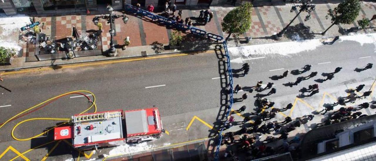 Decenas de curiosos observan detrás de la valla las labores de los bomberos en la zona del incendio.