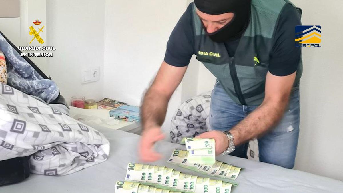 Un agente de la Guardia Civil cuenta los billetes de 100 decomisados en la operación