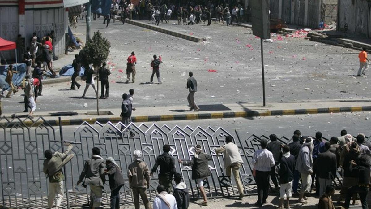 Partidarios del régimen del presidente Saleh, en primer término, atacan a manifestantes, este jueves, en Saná.