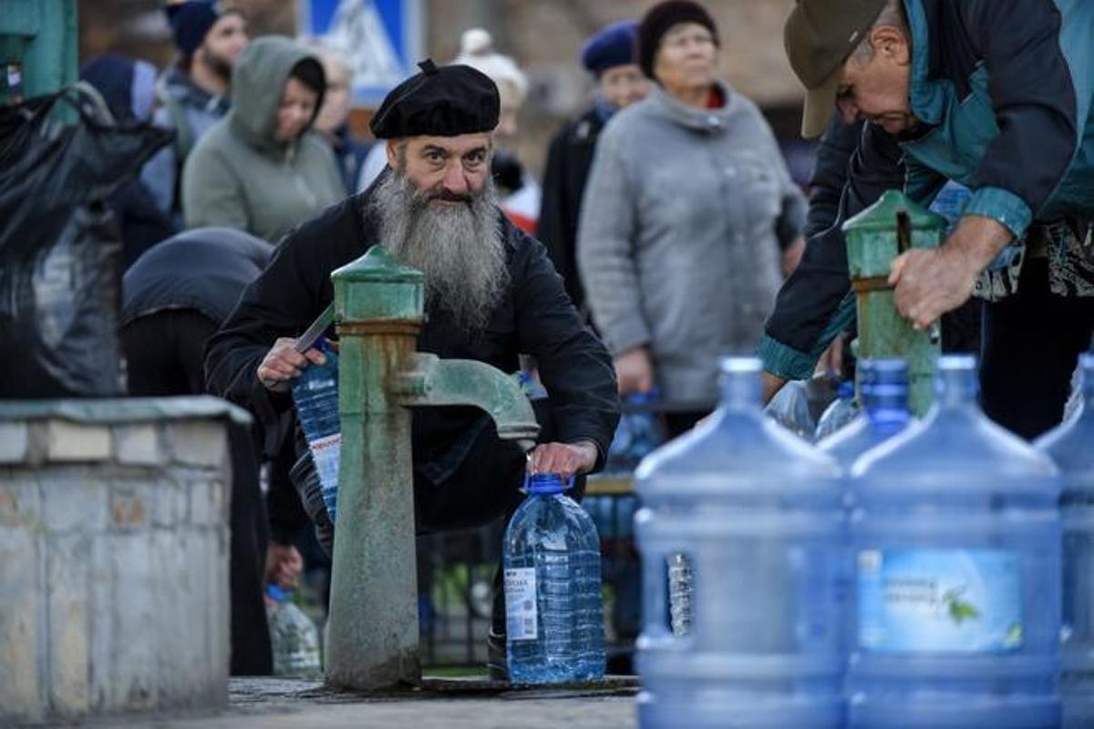 Kyiv (Ucrania), 31/10/2022.- La gente hace cola de una fuente, después de que parte de la capital ucraniana haya quedado sin luz ni suministro de agua por los bombardeos rusos.