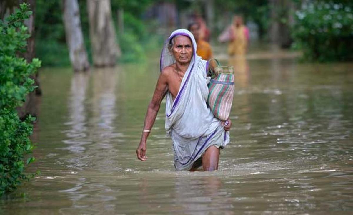 Una dona camina per un poble inundat al districte de Midnapore Occidental, a l’estat indi de Bengala Occidental. Almenys 3.000 famílies han estat afectades per les inundacions de diversos pobles al districte, provocades per les fortes pluges i l’alliberament d’aigua d’embassaments i preses a través del riu Damodar.