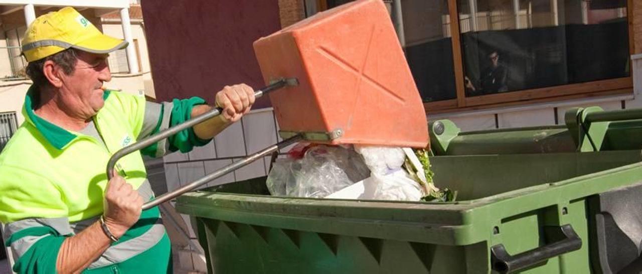 Un trabajador de la limpieza, volcando desperdicios en un contenedor en Almoradí.