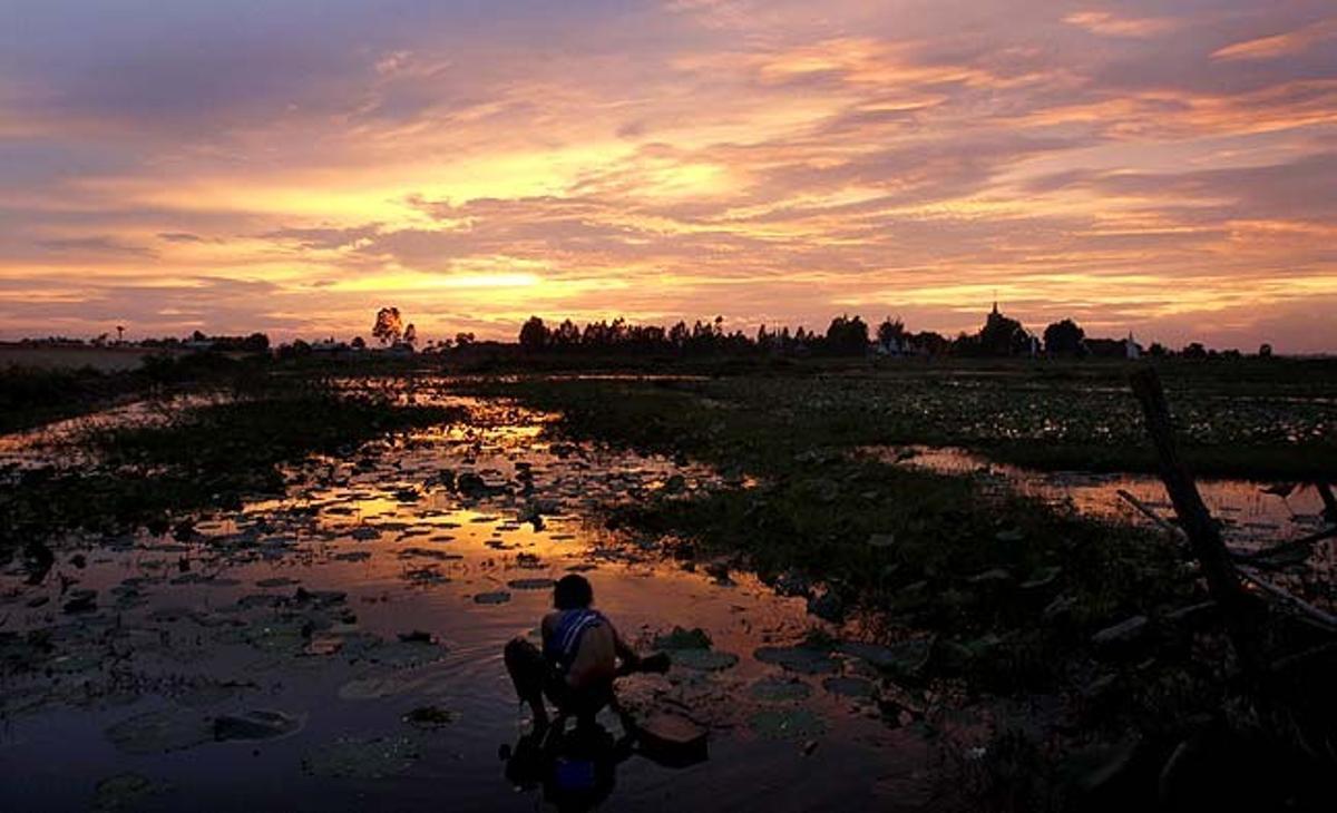 Un pagès cambodjà es banya a la nit en un llac a prop de casa seva al poblet de Kobsrov (Cambodja).