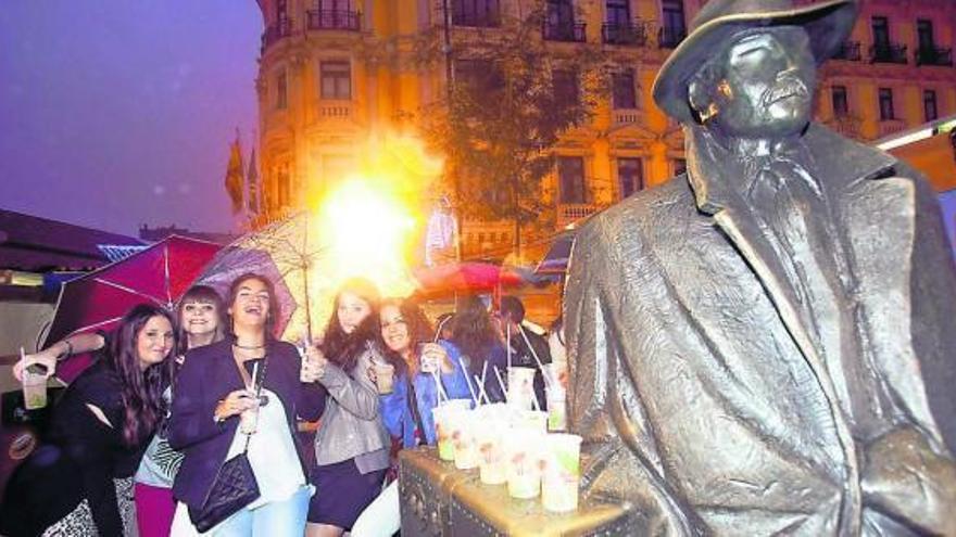 Un grupo de amigas posa con sus mojitos tras la escultura de «El viajero», en la plaza Porlier.