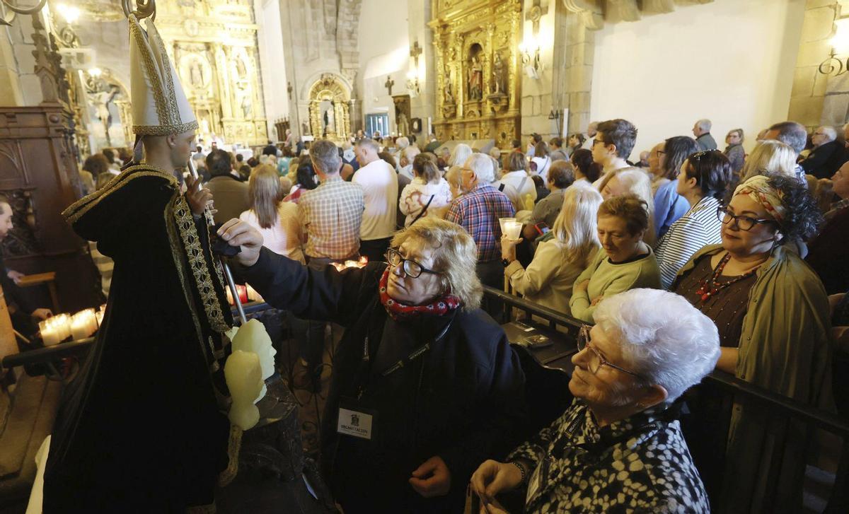 En la celebración no faltaron los ritos tradicionales de recoger el aceite milagroso, pasar por debajo del altar y tocar con un pañuelo la imagen del santo, a los que se unieron curiosas novedades, como el lanzamiento de la cerveza «Ollo Redondo», un muñeco de Santiago Peregrino y la primera Feria de Productos Monacales. | GUSTAVO SANTOS