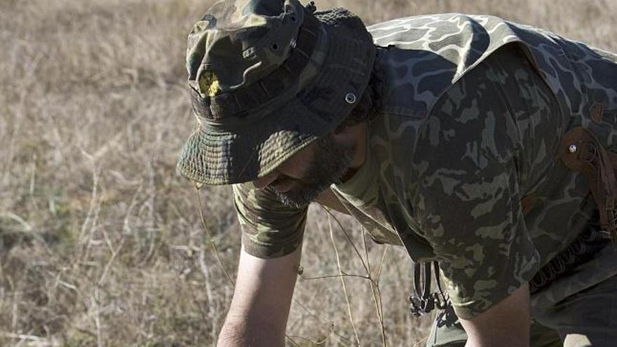 Un cazador acaricia al perro antes de cobrar una perdiz.