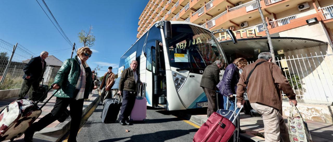 Turistas de la tercera edad, cargados con maletas, a las puertas de un hotel de Benidorm que trabaja habitualmente con el Imserso.