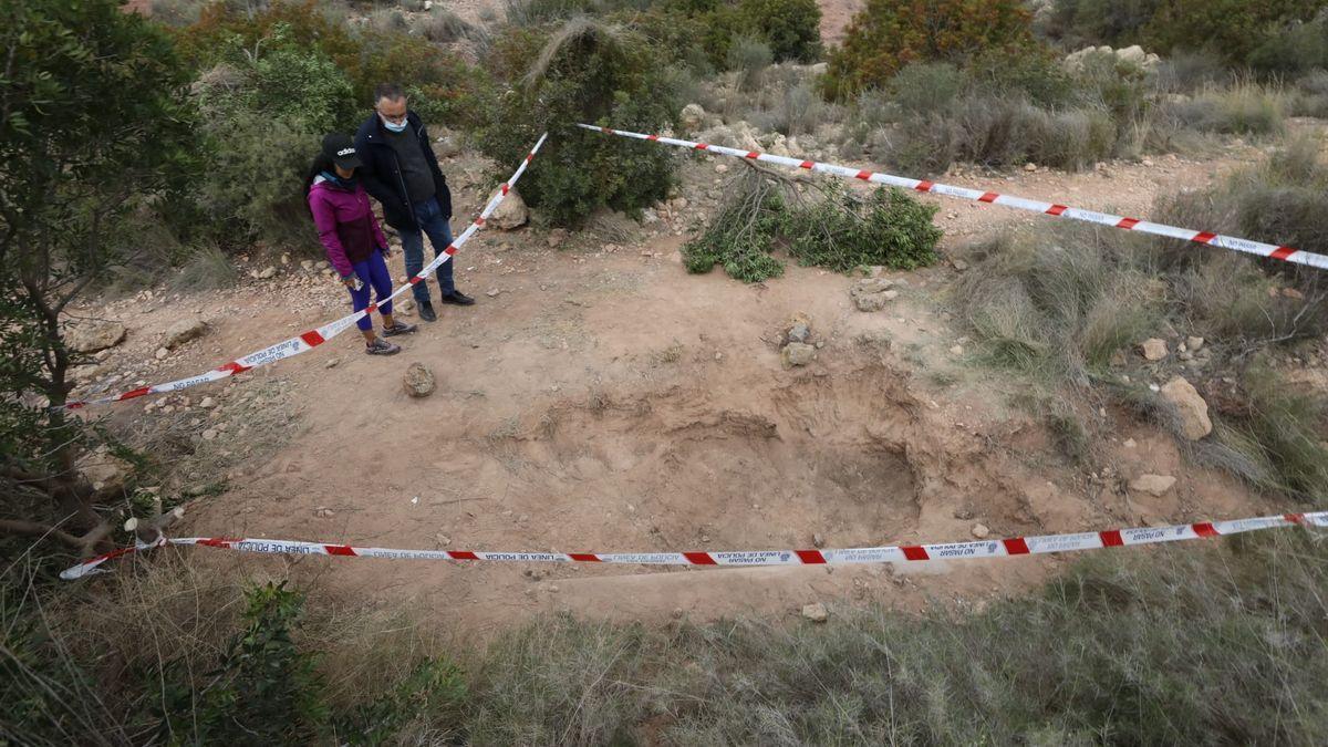 Dos personas miran el lugar donde estaban enterrados los cuerpos.