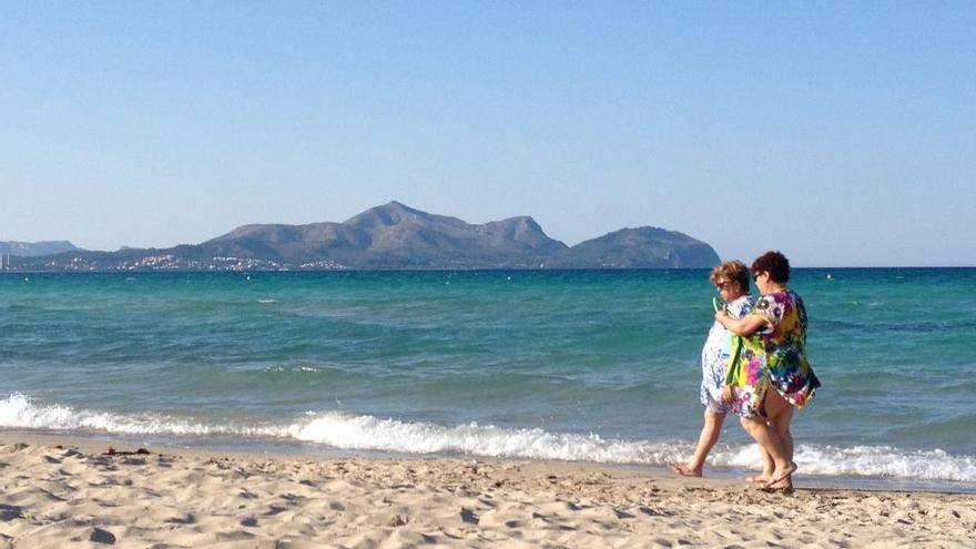 Dos bañistas pasean por la Playa de Muro.