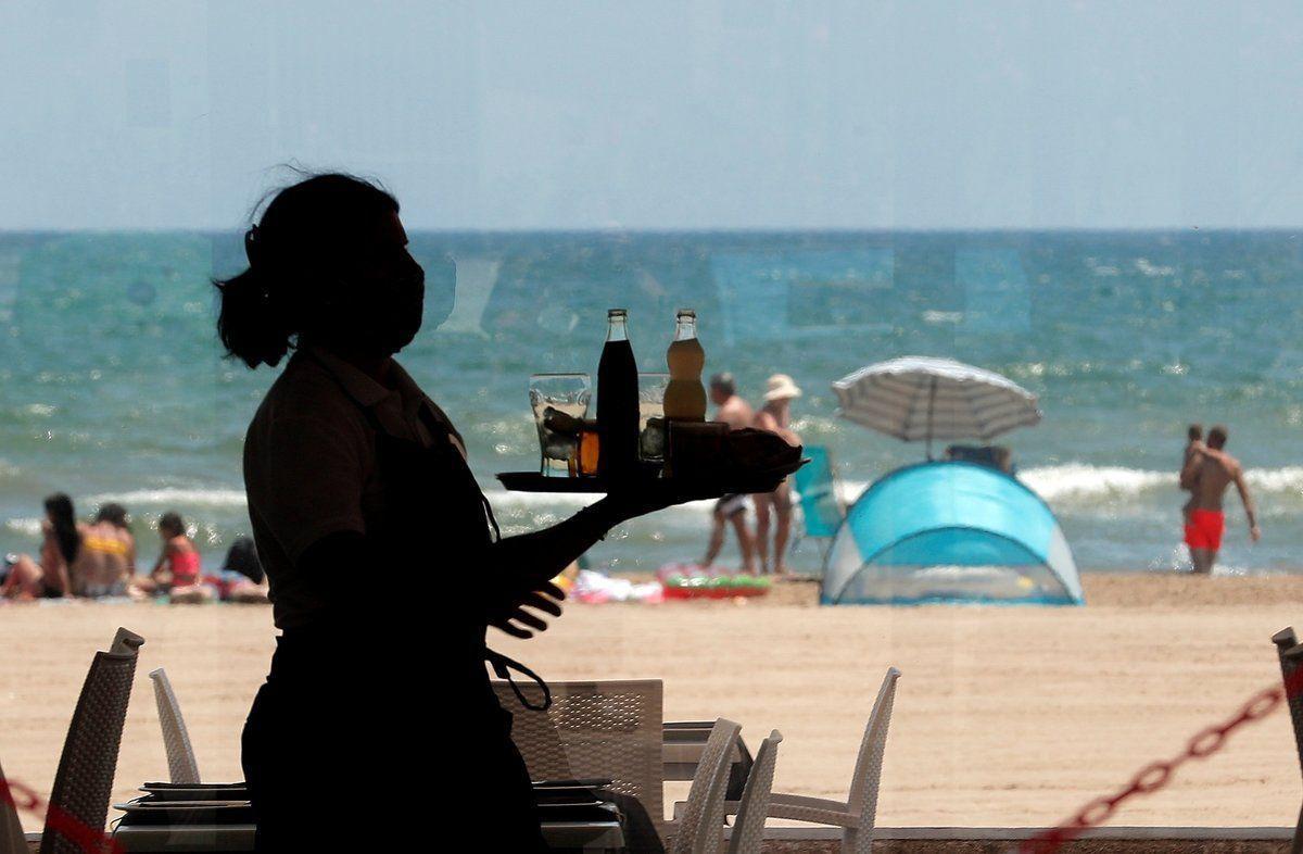 Una camarera lleva una bandeja con bebidas en un restaurante.