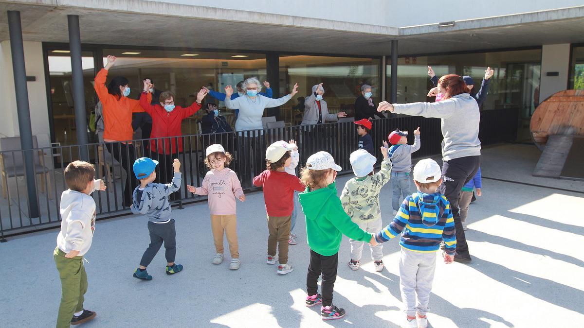 Usuarias del centro de día y niños de la escuela infantil, compartiendo un baile este martes en A Farixa. // IÑAKI OSORIO